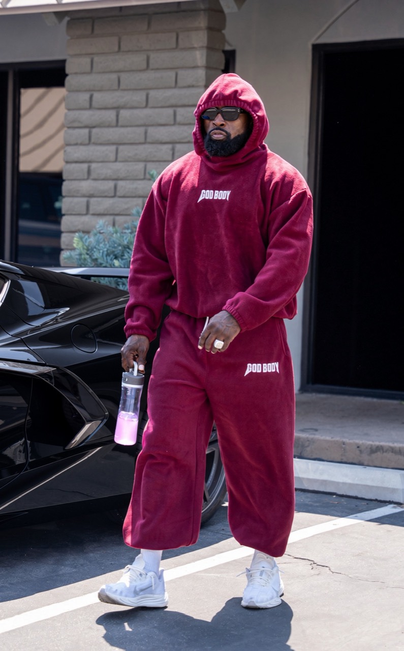 Mike Rashid in a red God Body outfit, sunglasses, and white sneakers