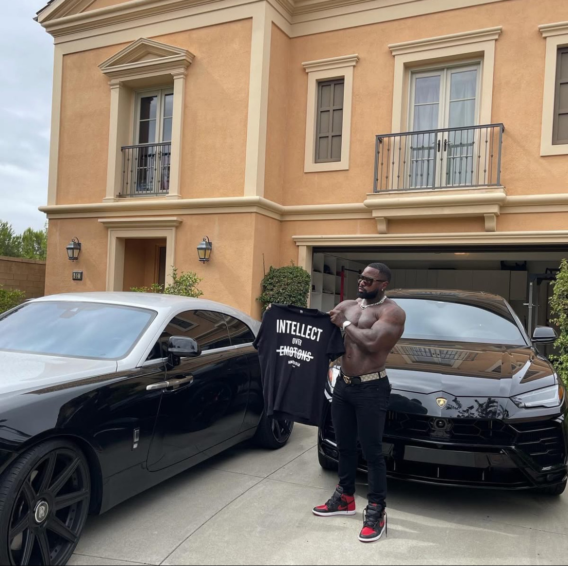 Mike Rashid holding an Intellect Over Emotions shirt while standing between two cars